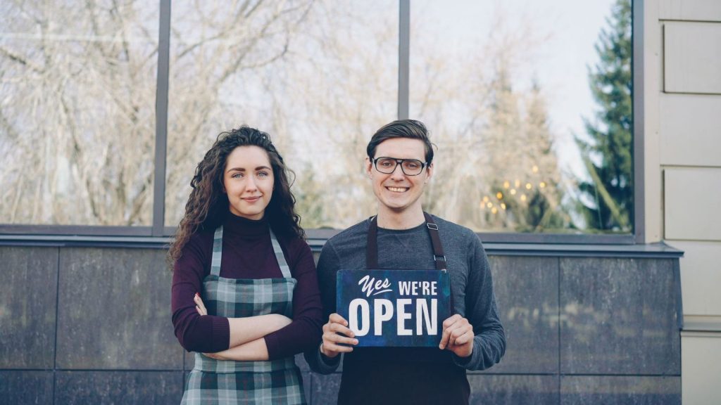Two business owners holding an open sign
